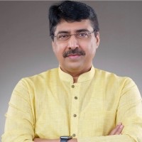 Formal portrait of Deepak Mhaskey in a pale yellow kurta, arms folded.