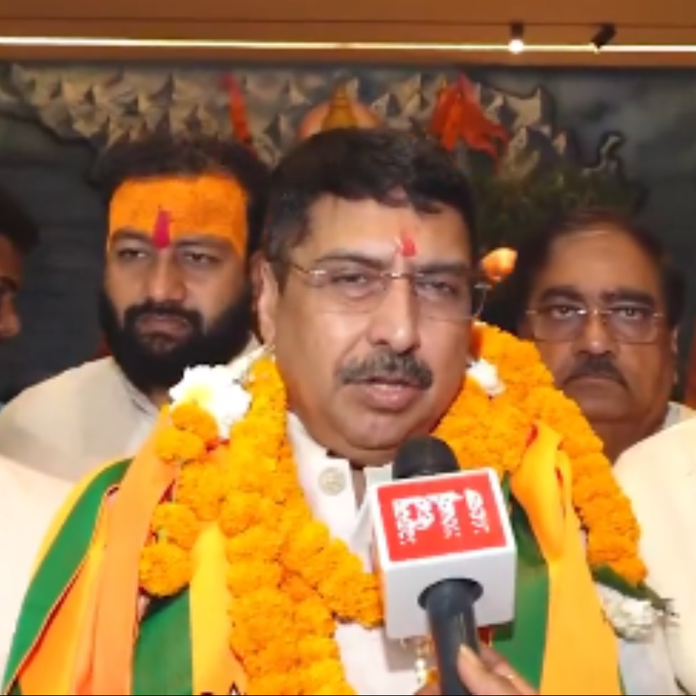 Deepak Mhaskey, wearing marigold garlands, speaking to reporters after his appointment as the BJP's National Convenor for social media.