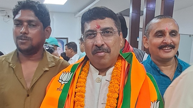Deepak Mhaskey, garlanded and wearing a BJP scarf, surrounded by party workers at an indoor gathering.