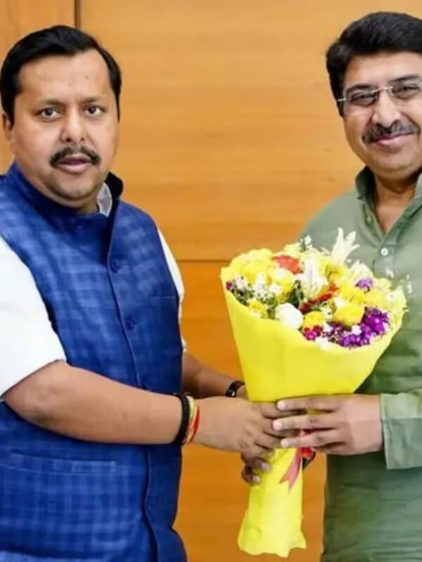 Deepak Mhaskey, in an olive kurta, receiving a large bouquet of yellow and white flowers from the BJP national president, who is wearing a blue Nehru jacket.